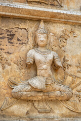 Over 500 years old Thewada sculpture on the wall of ancient temple in Thailand.