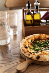 Pizza and water in glass jug on wooden table in vintage style. Italian restaurant background for your design.