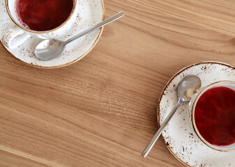 Red fruit tea in trendy ceramic white cups with brown decor on wooden table. Food background in rustic style. Copy space. Flat lay.