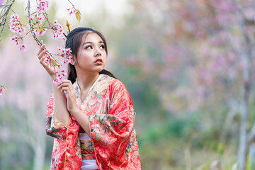 A young woman showing cherry blossoms on her hand under a cherry tree in Japan.