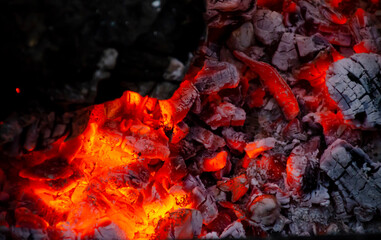 Burning log of wood close-up as abstract background. The hot embers of burning wood log fire. Firewood burning on grill.