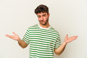 Young caucasian man isolated on white background doubting and shrugging shoulders in questioning...