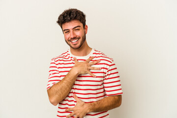 Young caucasian man isolated on white background laughs happily and has fun keeping hands on stomach.