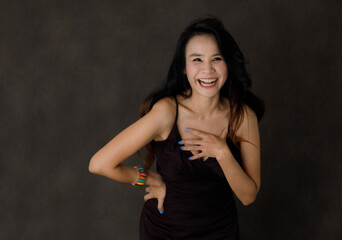 Happy laughing young Asian woman in studio