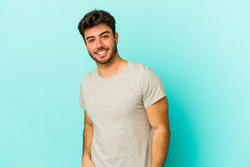 Young caucasian man isolated on blue background confident keeping hands on hips.