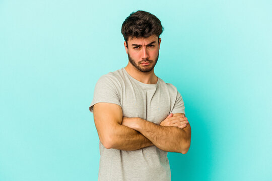 Young caucasian man isolated on blue background tired of a repetitive task.
