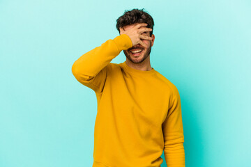 Young caucasian man isolated on blue background covers eyes with hands, smiles broadly waiting for a surprise.