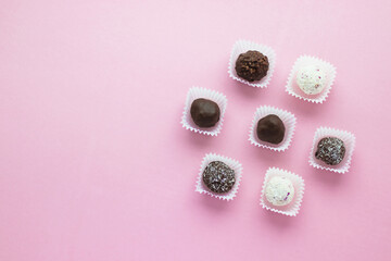 Tasty ball-shaped chocolate candies packed in small paper baskets on pink background. Romantic valentine's day day dessert. Delicious sweet. Minimal style. Flat lay, top view with copy scape.