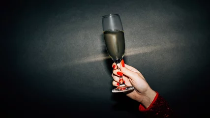  Birthday cheer. Holiday party. Happy celebration. Advertising background. Unrecognizable woman red manicure holding champagne glass isolated black light splash copy space. © golubovy