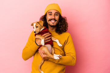 Young caucasian man holding his puppy isolated on pink background