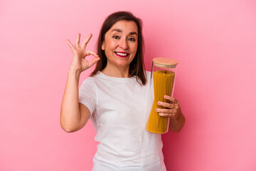 Middle age caucasian woman holding a pasta jar isolated on pink background cheerful and confident showing ok gesture.
