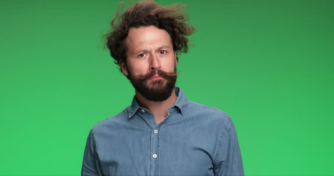 young casual man walking on his way, being distracted, touching his beard, thinking then figuring out and giving an ok sign