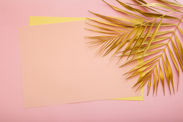 Fototapeta na wymiar Pink card copy space for text in frame made of Golden palm leaf. Tropical palm leave on pink background. Painted gold leave. Summer floral background.