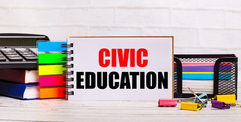 On a light wooden background, a calculator, multi-colored sticks and a notebook with the text CIVIC...