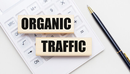 Wooden blocks with the text ORGANIC TRAFFIC lie on a light background on a white calculator. Nearby...