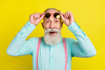 Photo portrait of bearded gentleman amazed surprised taking off sunglass isolated vibrant yellow...