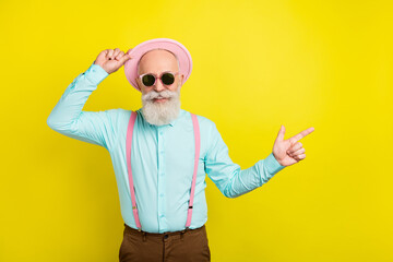 Photo portrait of old man wearing sunglass pink hat pointing finger empty space isolated vivid yellow color background