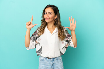 Young woman over isolated blue background counting seven with fingers