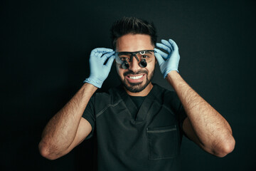 Mixed race male doctor smiling big while posing for portrait wearing surgical glasses and gloves 