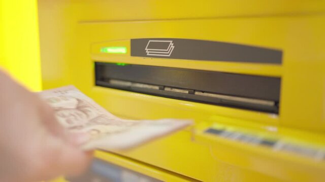 Asia woman hand pick up money at the ATM machine in the department store. Use personal identification number. Withdrawal money. Finance, technology and security concept. 
