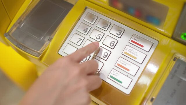Side view of caucasian woman hand entering put the passcode on the ATM machine keypad at the bank. Use personal identification number. Finance, technology and security concept. 