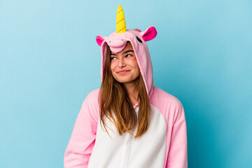 Young caucasian woman wearing a unicorn pajama isolated on blue background dreaming of achieving goals and purposes