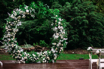 Round arch for a wedding ceremony of green branches and flowers in the garden