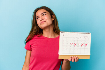 Young caucasian woman holding a calendar isolated on pink background dreaming of achieving goals and purposes