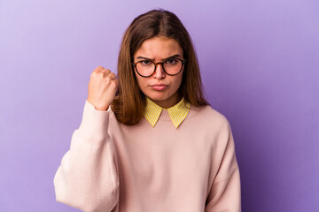 Young caucasian woman isolated on purple background showing fist to camera, aggressive facial expression.