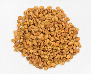 pile of whole fenugreek seeds close up on gray