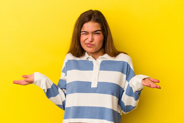 Young caucasian woman isolated on yellow background doubting and shrugging shoulders in questioning...