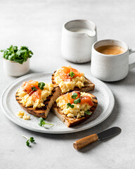 scrambled eggs toast with salmon and microgreens on a white ceramic plate, selective focus