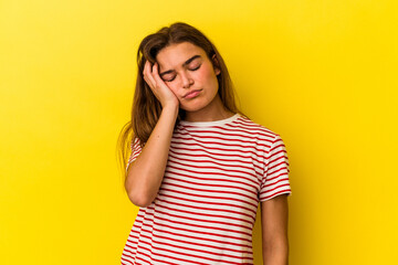 Young caucasian woman isolated on yellow background tired and very sleepy keeping hand on head.