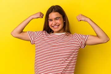 Young caucasian woman isolated on yellow background showing strength gesture with arms, symbol of feminine power