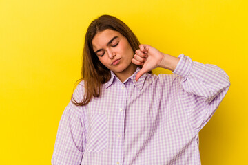 Young caucasian woman isolated on yellow background showing a dislike gesture, thumbs down....