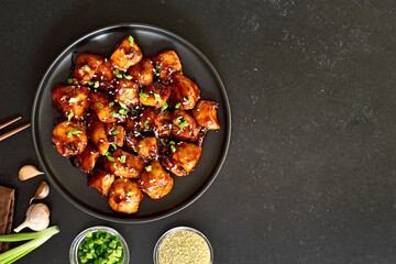 Teriyaki chicken on plate over black stone background