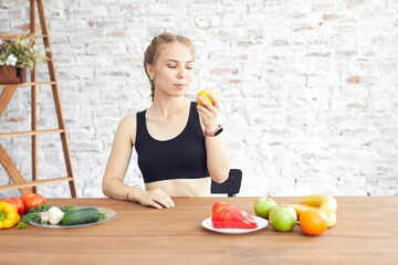 Sad girl looks at the vegetables lying on the table. Dieting habits changes. Woman hates vegetarian diet.