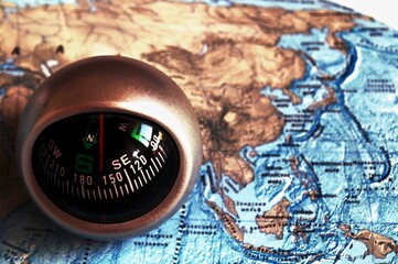 The desktop compass is located on the world map. Travel and travel. The compass points south