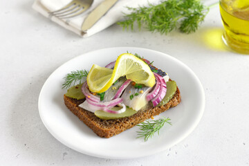Sandwich with herring fish and pickles cucumbers