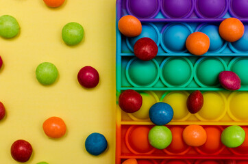 New popular silicone colorful antistress pop it toy for child on yellow background. View from above. Copy space. Simple dimple
