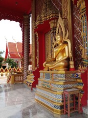statue of a sitting golden buddha in a temple in thailand