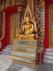 statue of a sitting golden buddha in a temple in thailand