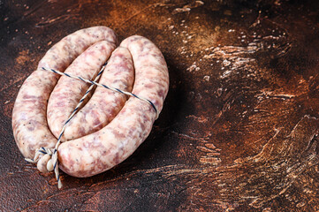 Raw sausages from pork and beef meat on the wooden board. Top view. Dark background. Copy space