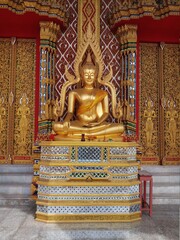 golden statue of a sitting buddha in a temple in thailand