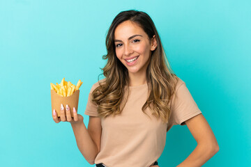 Young woman holding fried chips over isolated background posing with arms at hip and smiling