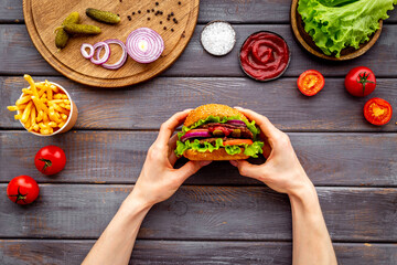 Female hands holding hamburger. Sandwich burger with ingredients. Fastfood meal background
