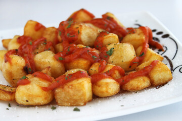 ración de patatas bravas con salsa de tomate y perejil