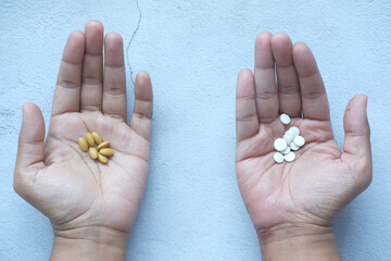 herbal medicine and medical pills on palm of hand 