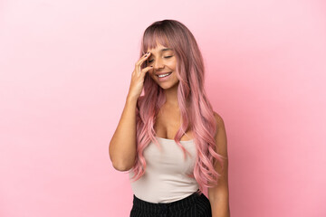 Young mixed race woman with pink hair isolated on pink background smiling a lot