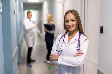 Portrait of a young woman doctor in a clinic with colleagues in the background